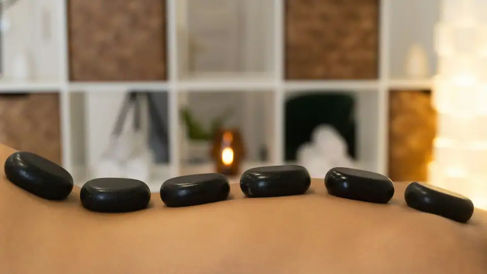 Spa ortamında sırt üzerine dizilmiş sıcak masaj taşları